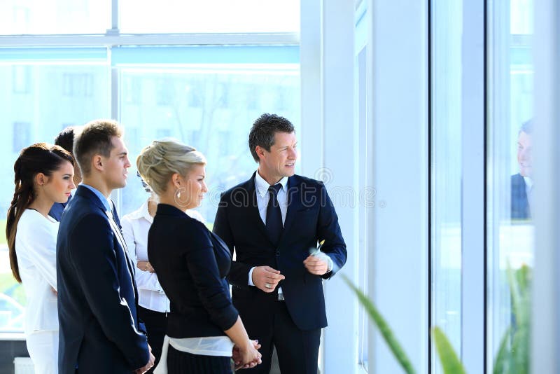 Group of business people looking out the window,standing in the lobby of the office.