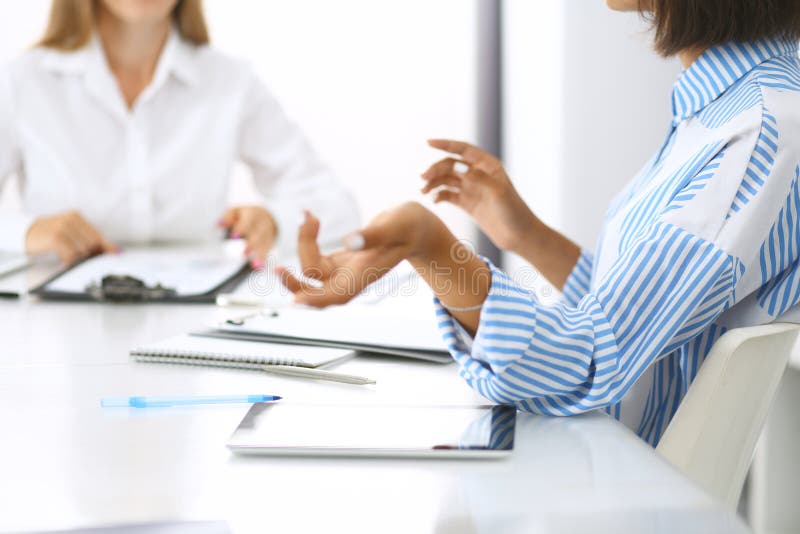 Group of business people at meeting in office, close-up. Team of two women discussing deal. Negotiation concept