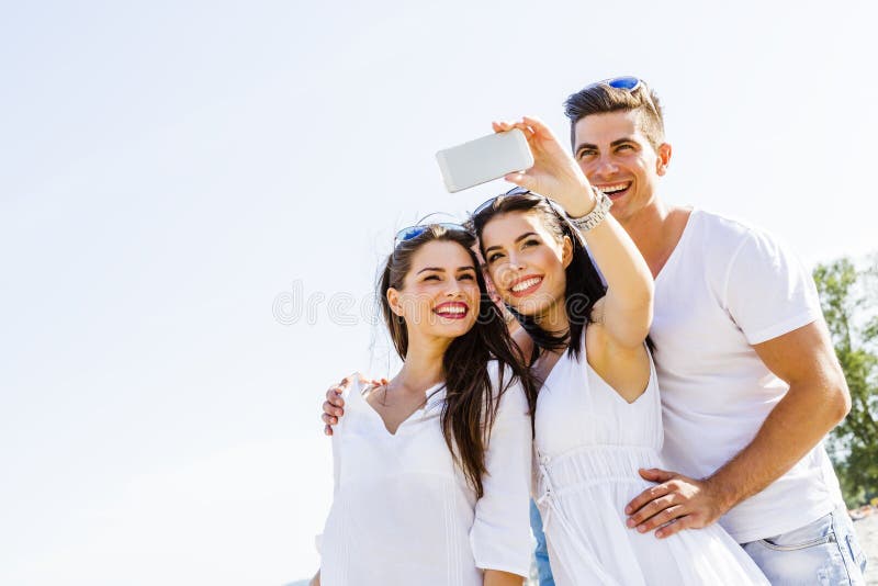Group of cheerful and beautiful young people taking photos of th stock photos
