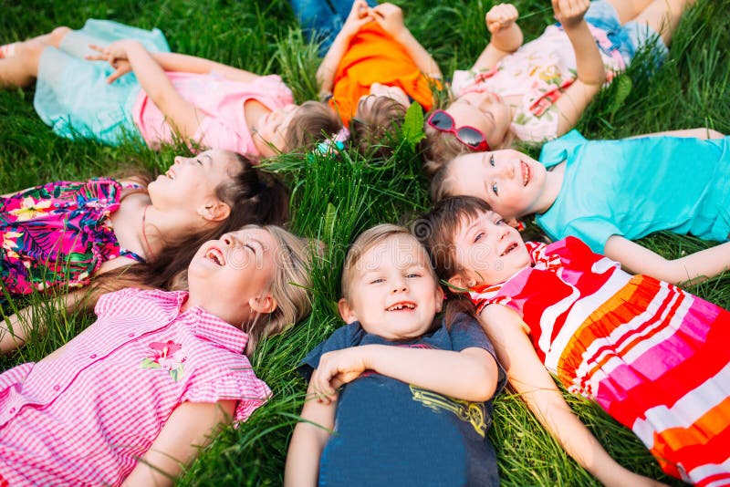A group of children lying on the green grass in the Park. The interaction of the children. stock image A group of children lying on the green grass in the Park. The interaction of the children. stock image