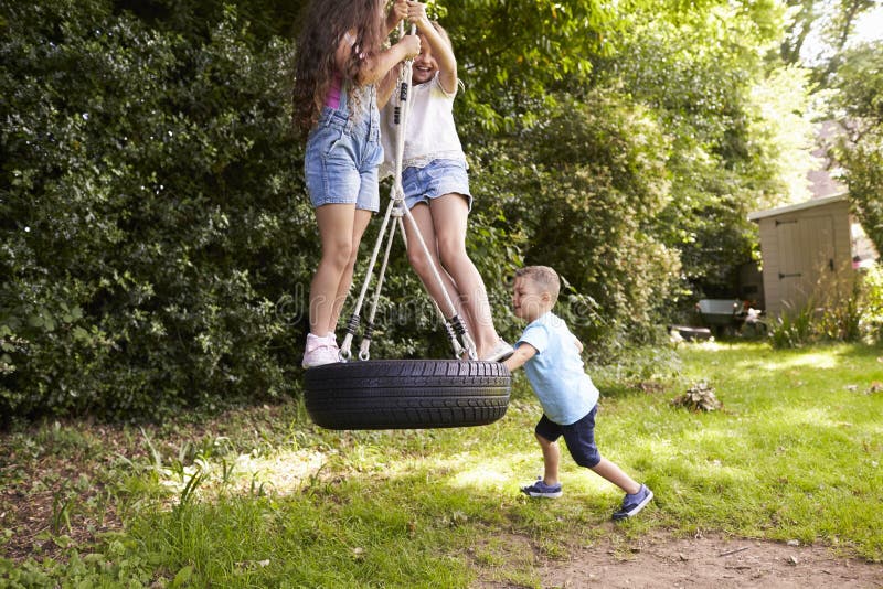 Group Of Children Playing On Tire Swing In Garden royalty free stock photography Group Of Children Playing On Tire Swing In Garden royalty free stock photography