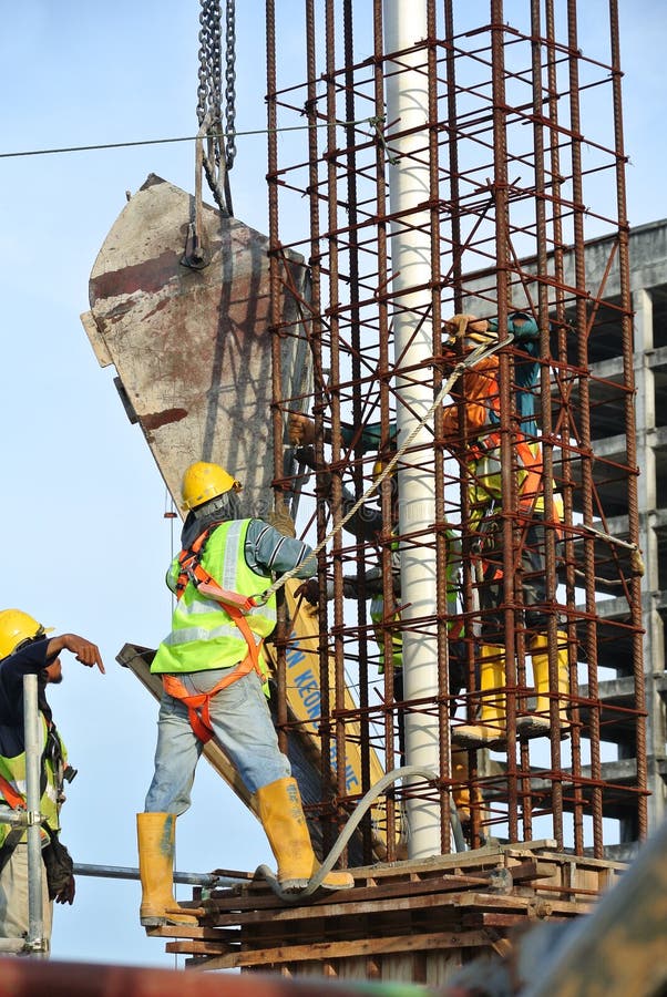 A Group Of Construction Workers Pouring Concrete Into Column Form Work