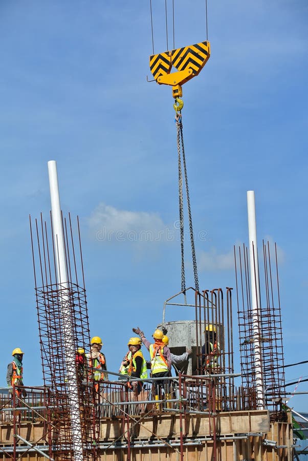 A Group of Construction Workers Pouring Concrete into Ground Beam Form