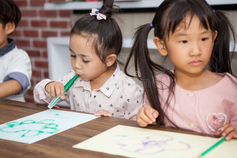 group of Cute little girl and boy student blowing color pen painting  together with nursery teacher in classroom school . Happy