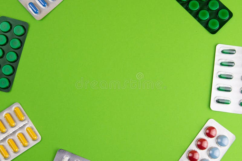 Group of different pills arranged in shape of circle on green background royalty free stock images