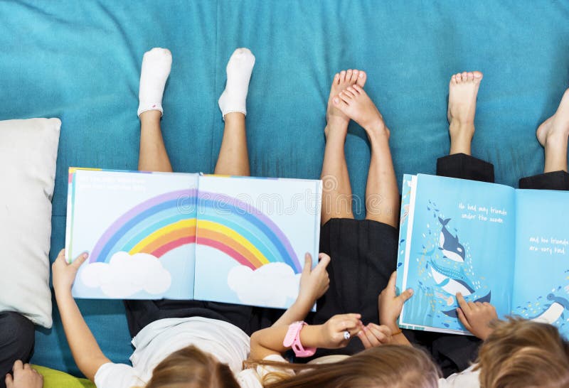 Group of Diverse Young Students Reading Children Story Book Together royalty free stock images