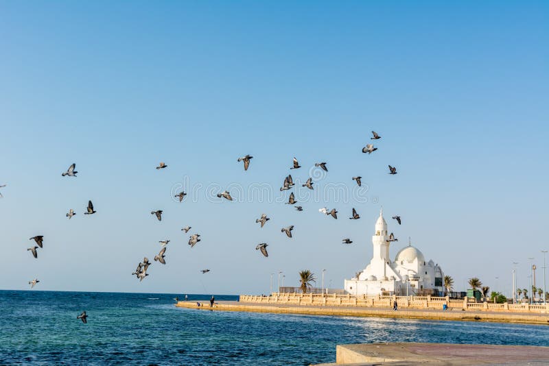 A group of doves flying over white mosque at the Jeddah Corniche coastal resort park near red sea in Jeddah, Kingdom of Saudi