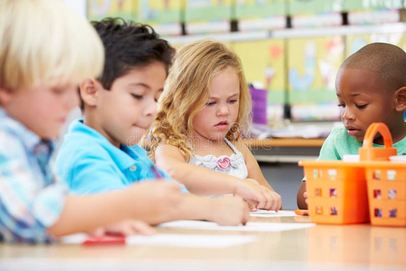 Group Of Elementary Age Children In Art Class Using Coloured Crayons