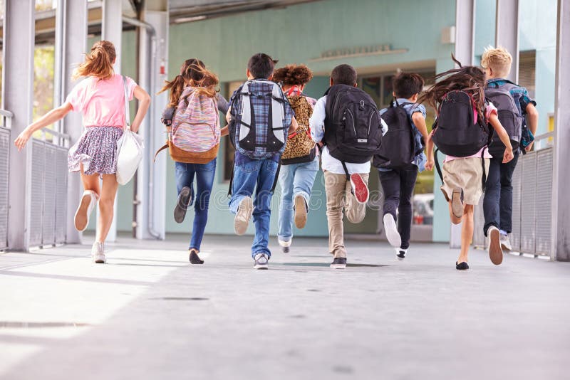 Group of elementary school kids running at school, back view