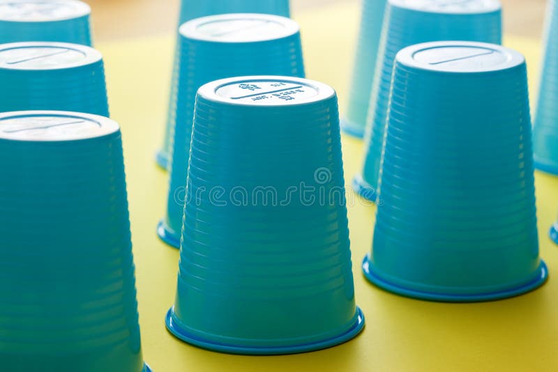 Group of Empty Blue Plastic Disposable Cups Over a Yellow Background