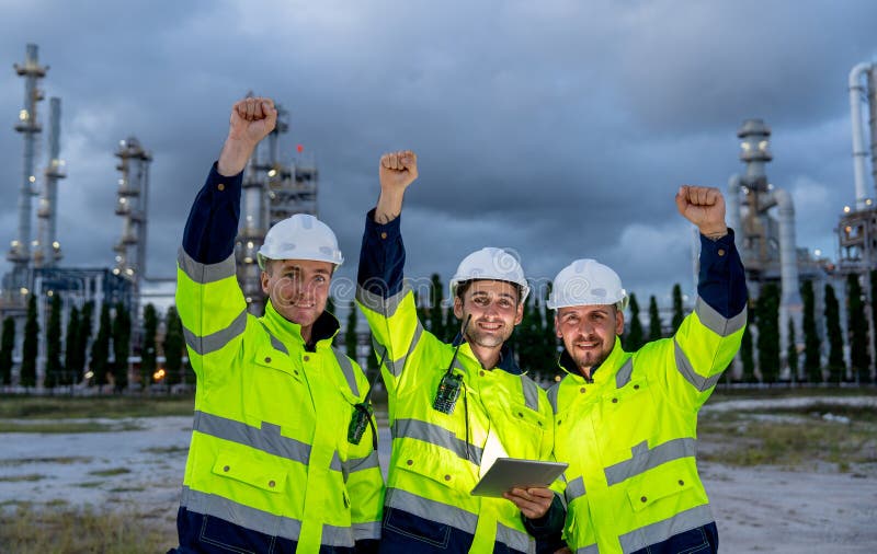 Group of engineer or technician workers stand in front petrochemical factory and raise their hands up to express happiness stock photography
