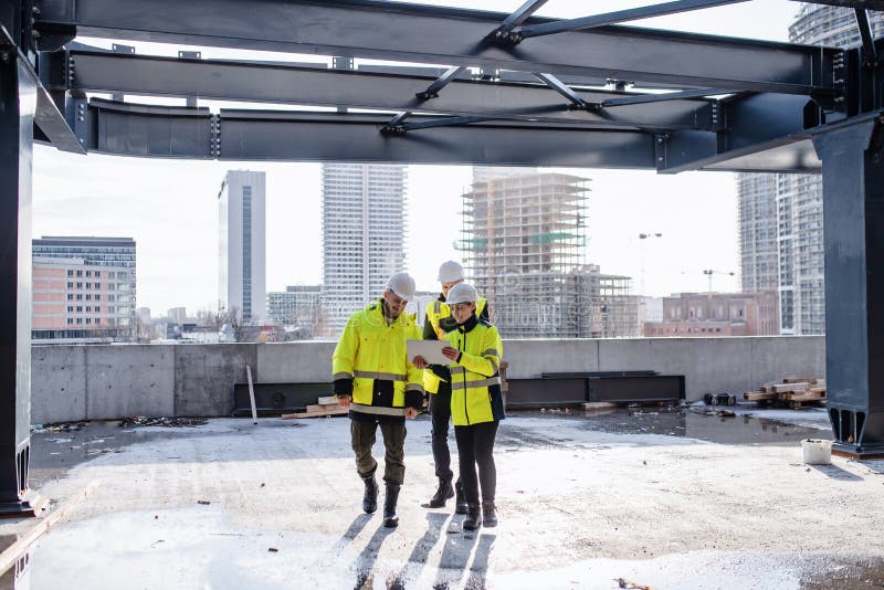 Group of engineers standing outdoors on construction site, using tablet. royalty free stock image