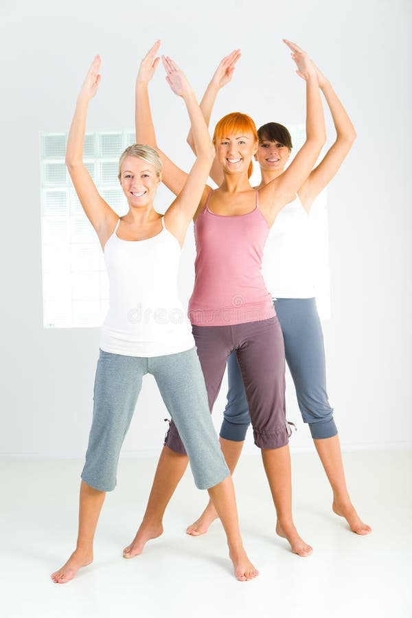 Three women dressed sportswear standing with hands raised up and looking at camera. Front view. Three women dressed sportswear standing with hands raised up and looking at camera. Front view.