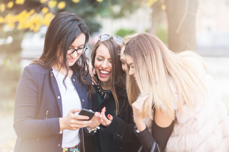 Group of four girl friends looking at phone on the selfie they w royalty free stock photos Group of four girl friends looking at phone on the selfie they w royalty free stock photos