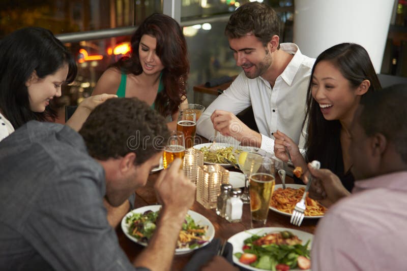 Group of Friends Enjoying Evening Meal in Restaurant Stock Image
