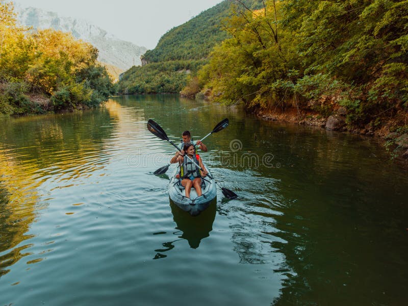 A group of friends enjoying fun and kayaking exploring the calm river, surrounding forest and large natural river royalty free stock image