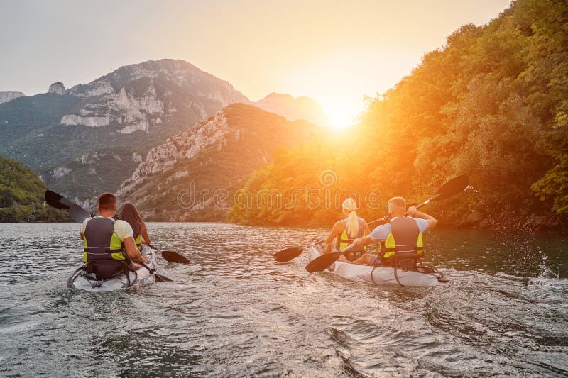 A group of friends enjoying fun and kayaking exploring the calm river, surrounding forest and large natural river royalty free stock image