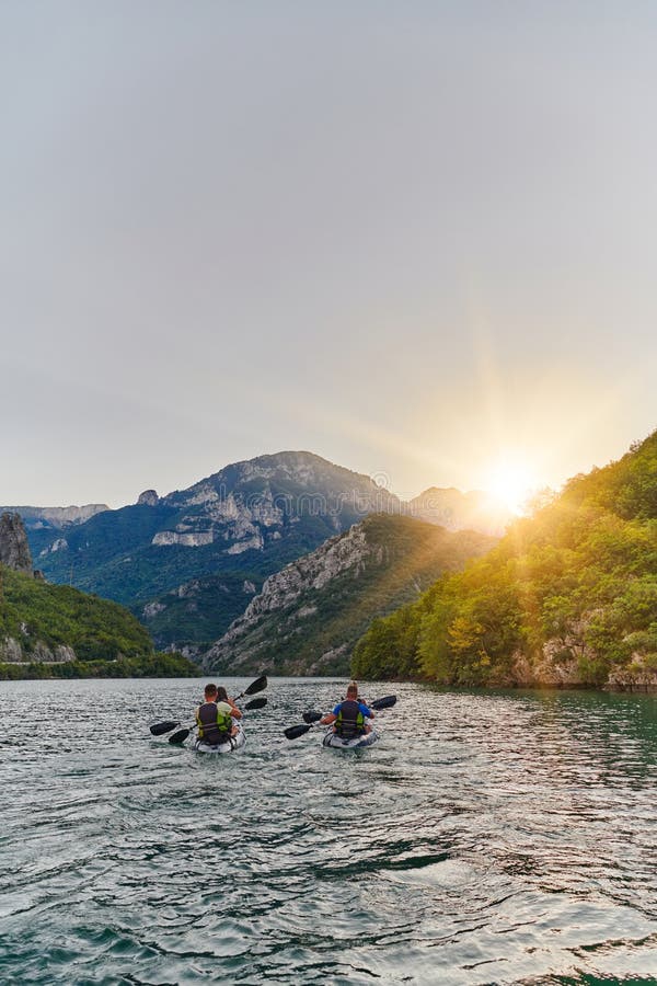 A group of friends enjoying fun and kayaking exploring the calm river, surrounding forest and large natural river stock photography