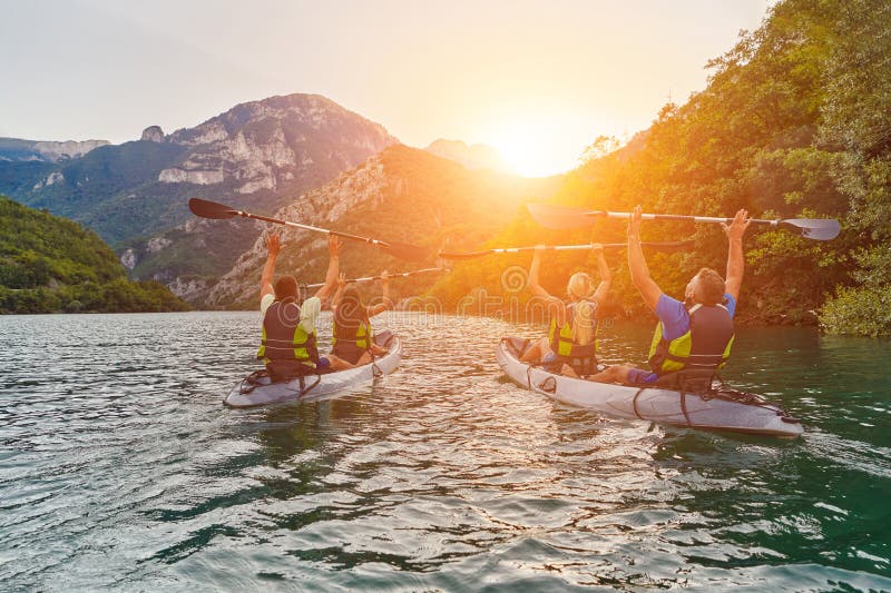 A group of friends enjoying fun and kayaking exploring the calm river, surrounding forest and large natural river stock photo