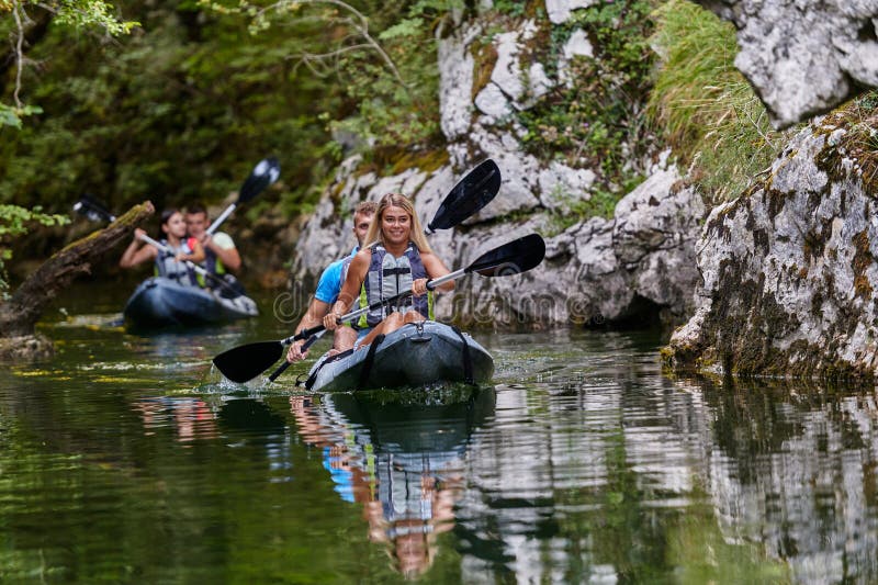 A group of friends enjoying having fun and kayaking while exploring the calm river, surrounding forest and large natural stock photo
