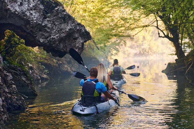 A group of friends enjoying having fun and kayaking while exploring the calm river, surrounding forest and large natural royalty free stock photos