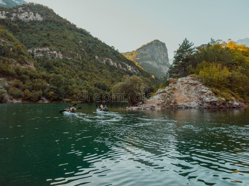A group of friends enjoying having fun and kayaking while exploring the calm river, surrounding forest and large natural stock photos