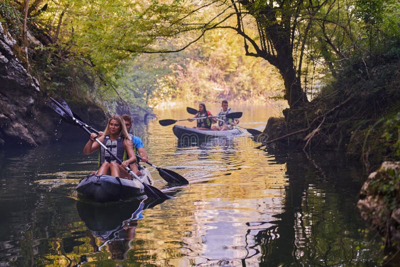 A group of friends enjoying having fun and kayaking while exploring the calm river, surrounding forest and large natural royalty free stock photos