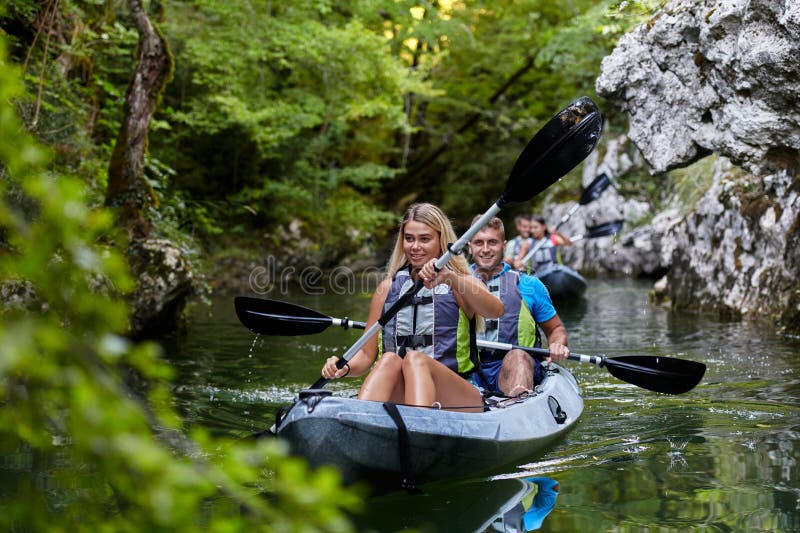 A group of friends enjoying having fun and kayaking while exploring the calm river, surrounding forest and large natural royalty free stock photography