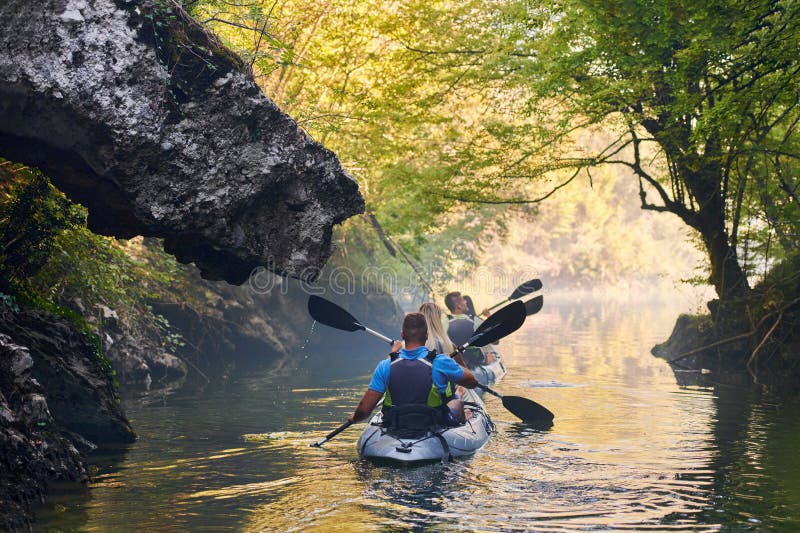 A group of friends enjoying having fun and kayaking while exploring the calm river, surrounding forest and large natural stock photography