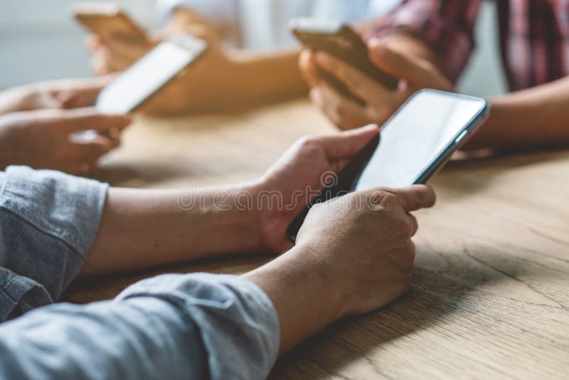 Group of friends playing app games in mobile phone and online together. Hands are holding smartphone circle on the table