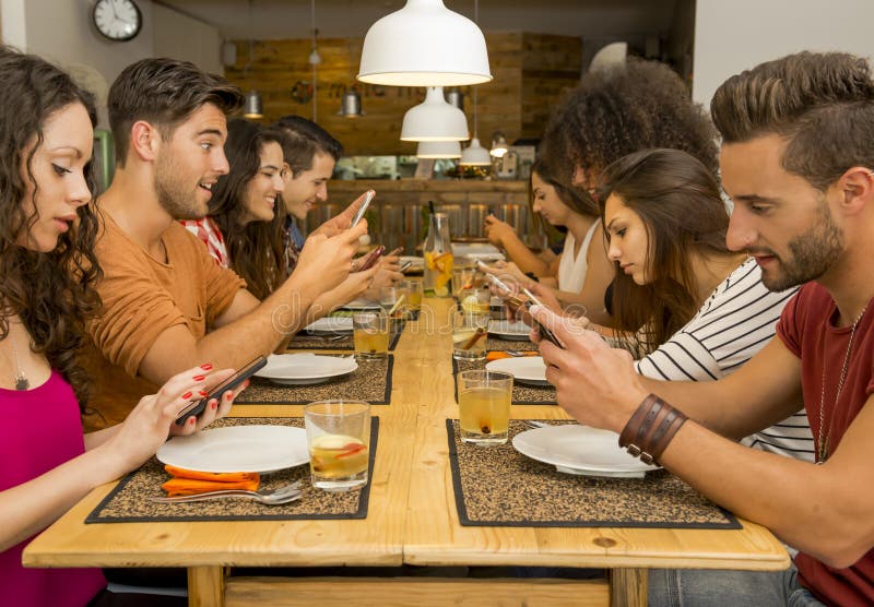 Social but not social. Group of friends at a restaurant with all people on the table occupied with cellphones royalty free stock photos