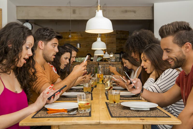 Social but not social. Group of friends at a restaurant with all people on the table occupied with cellphones royalty free stock photo