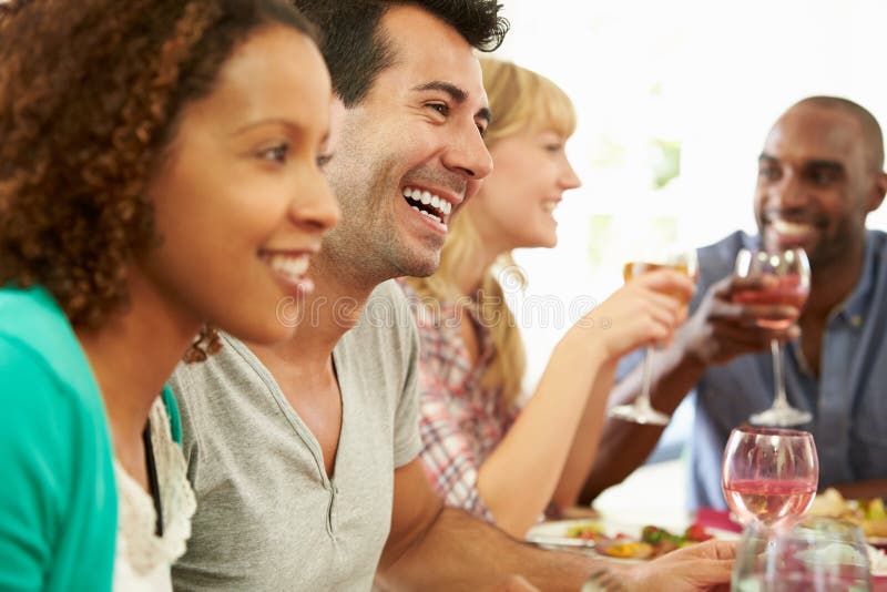 Gruppo Di Amici Seduti Attorno Ad Un Tavolo Con La Cena Di Partito, Parlando Tra Di Loro Sorridendo.