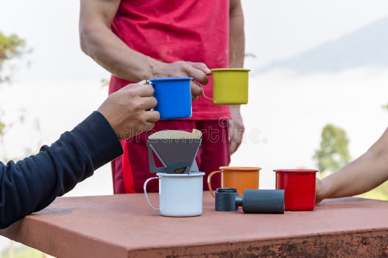 Group of friends talking and having coffee outdoor on misty mountain.