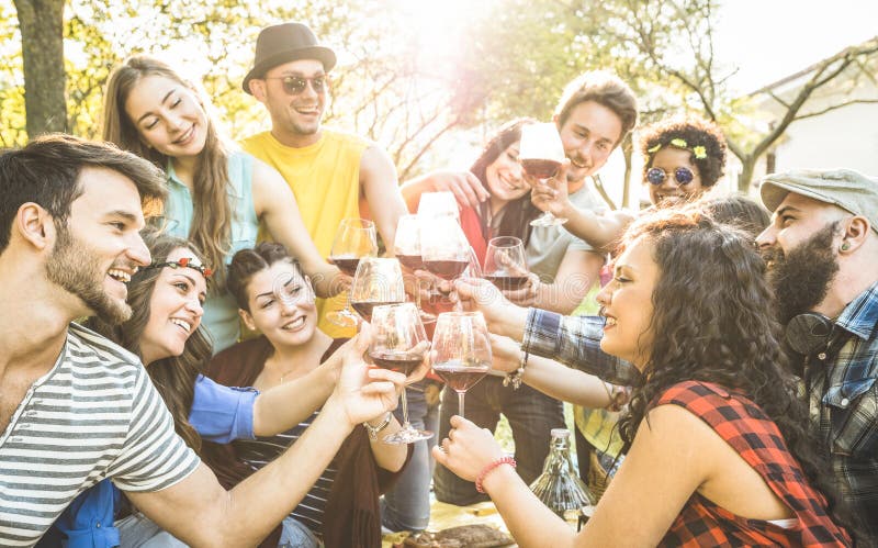 Gruppo di amici che brindano vino rosso di divertimento all'aria aperta tifo al barbecue picnic Giovani per godersi l'estate di tempo insieme a pranzo festa in giardino.