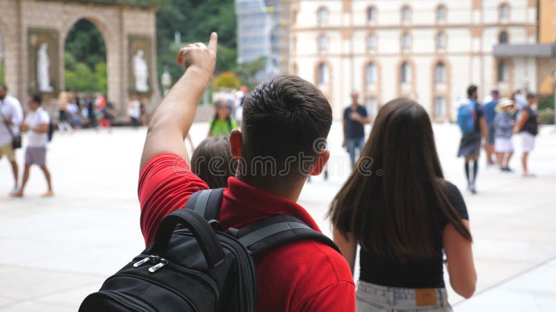 Group of friends walking and exploring tourist place. Young man pointing to something to her girlfriends during travel