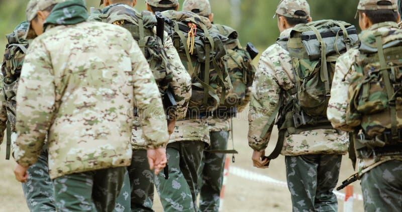 Group of Fully Equipped and Armed Soldiers Walking Forward Outwards Camera in Desert Environment.