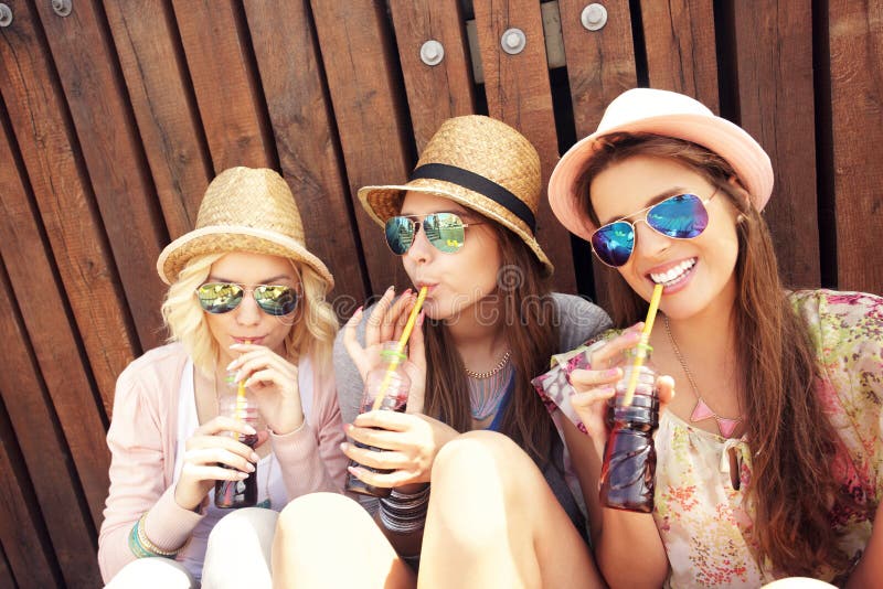 Group of girl friends drinking soda on the pier stock images Group of girl friends drinking soda on the pier stock images