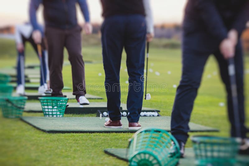 Group of Golfers Practicing and Training Golf Swing on Driving Range