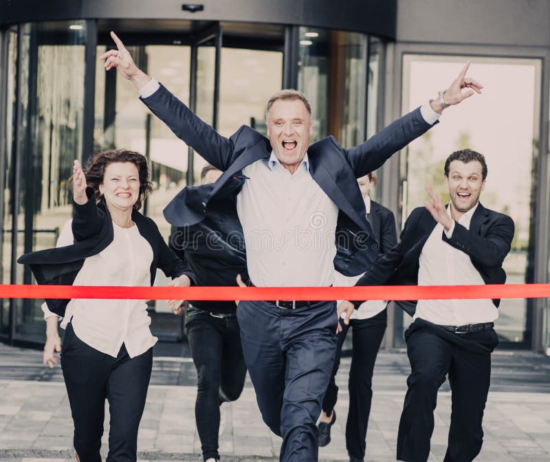 Gruppe von glücklich Geschäftsleute ausführen von office-Gebäude überqueren, die red-ribbon Ziellinie.
