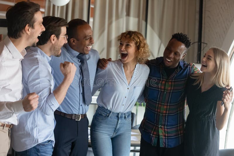 Group of happy excited diverse employees hugging, shouting for joy, celebrating teamwork success, win, good job result, achieve. Multiethnic business staff, united team of interns, workers portrait