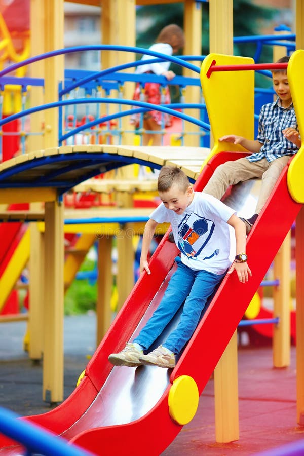 Group of happy kids sliding on colorful playground stock photos Group of happy kids sliding on colorful playground stock photos