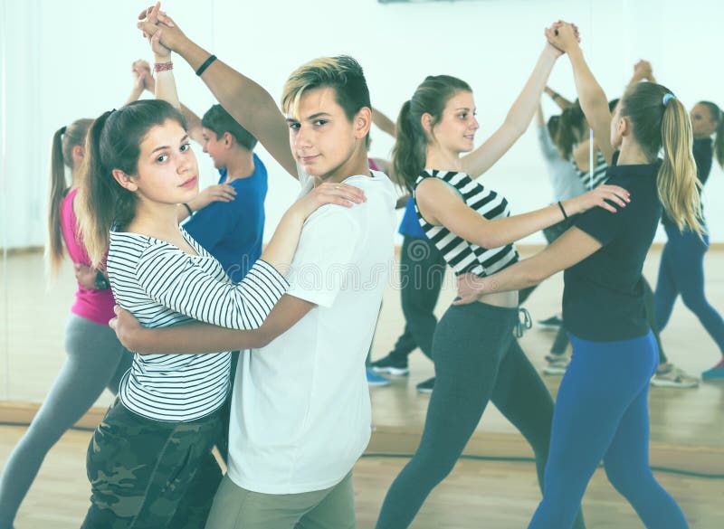 Group of joyous teenagers dancing tango in dance studio