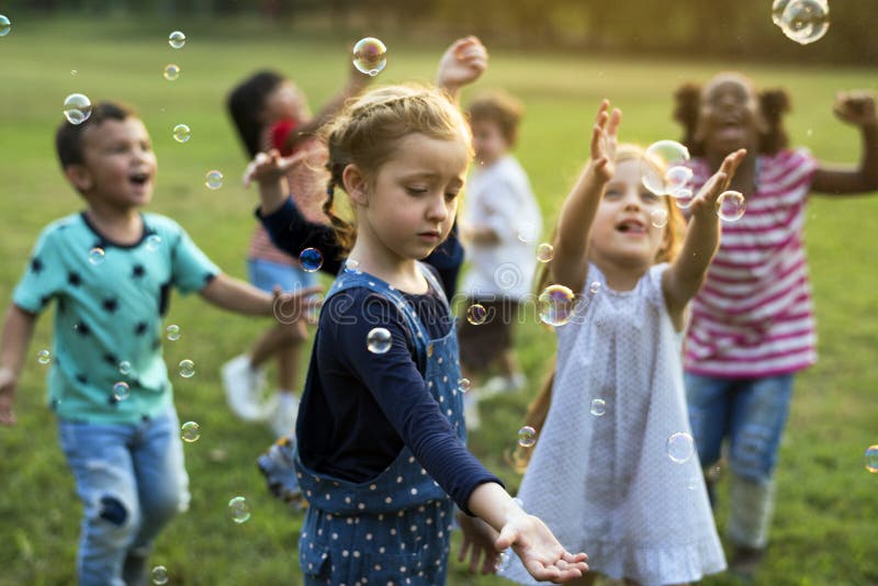 Gruppo da ASILO amici soffiando bolle divertimento.