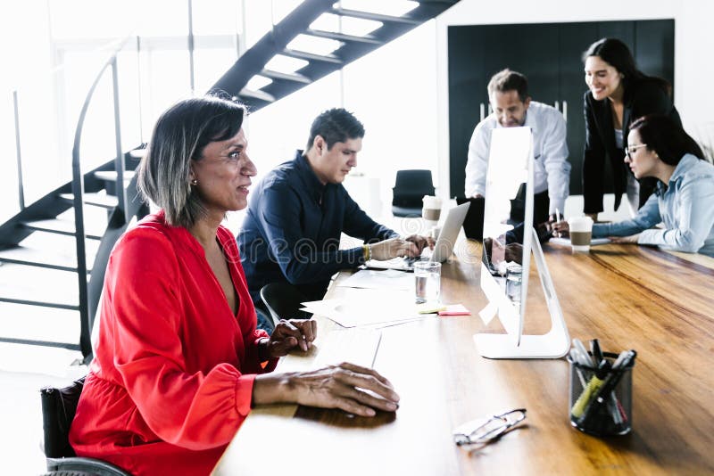 Group of latin office employees developing business strategies using digital devices at workplace in Mexico City stock image
