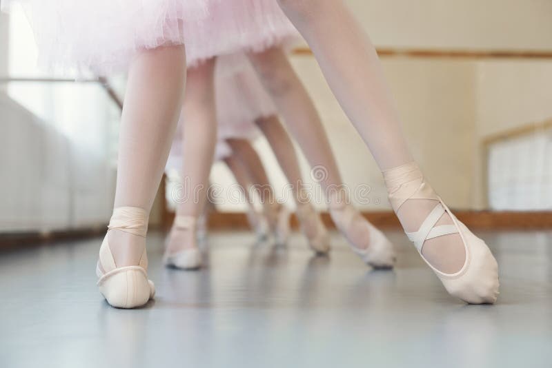 Grupo de pequeno bailarinas capacitación pierna posición sobre el la clase, copiar espacio.