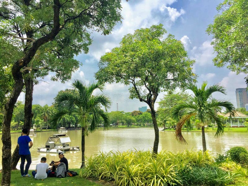 A group of locals relaxing under the shade of a tree along the lake of Lumpini Park on a hot day in downtown Bangkok. Lumpini Park, Bangkok, Thailand - May 18th royalty free stock photos A group of locals relaxing under the shade of a tree along the lake of Lumpini Park on a hot day in downtown Bangkok. Lumpini Park, Bangkok, Thailand - May 18th royalty free stock photos