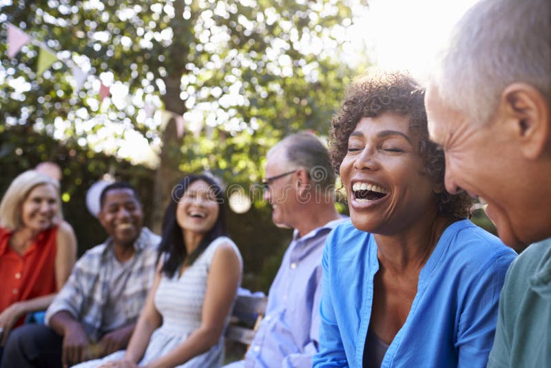 Group Of Mature Friends Socializing In Backyard Together