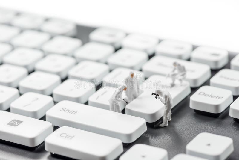 Group of miniature criminalists inspecting computer keyboard. Cybercrime concept stock photography Group of miniature criminalists inspecting computer keyboard. Cybercrime concept stock photography