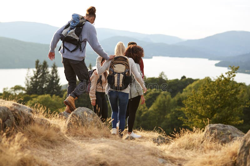 A group of mixed race young adult friends descending after a mountain hike, back view stock image A group of mixed race young adult friends descending after a mountain hike, back view stock image